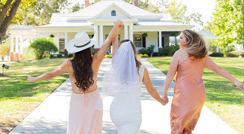 Bride and bridesmaids walking toward Hamilton Place venue, capturing a joyful wedding moment in a scenic South Georgia setting.